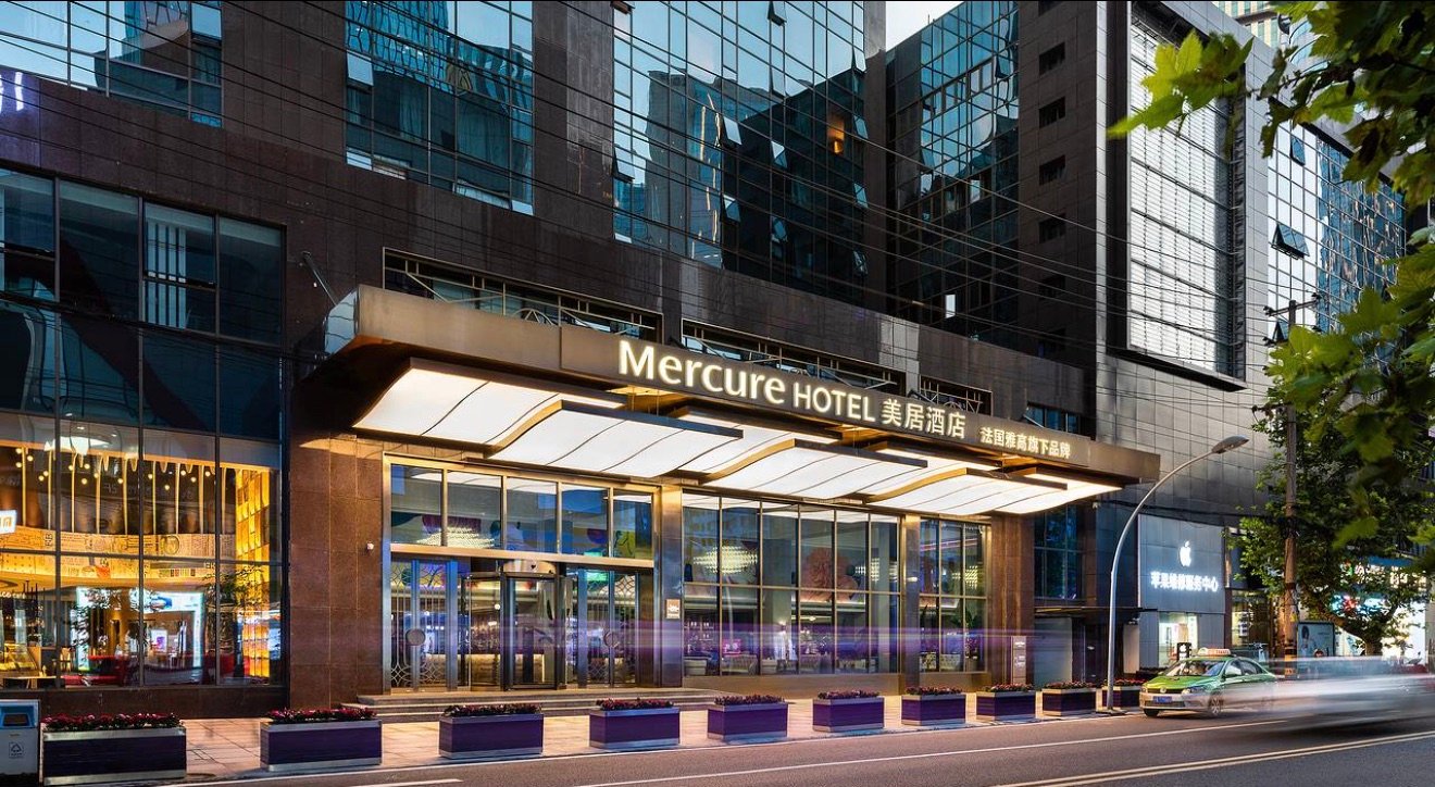 Evening street entrance of the Mercure hotel in Chengdu's Taikoo Li area, with warm lighting under the canopy and the hotel sign above.